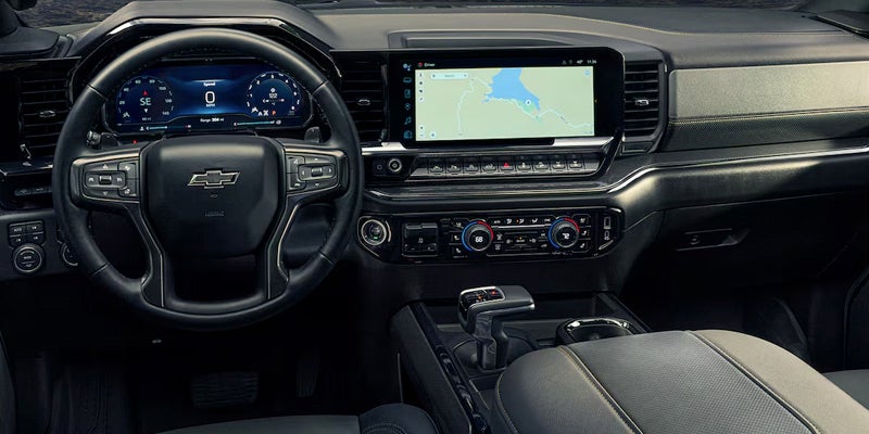 View of the 2025 Chevy Silverado's front dashboard from the front passengers point of view. Steering wheel, temperature controls, and touch screen are visible.