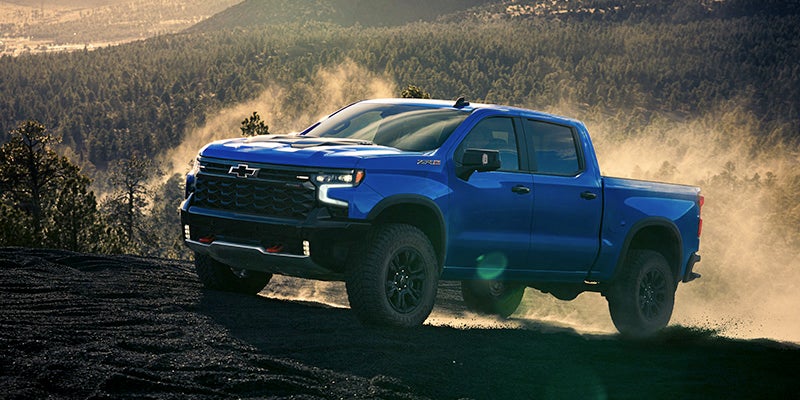 Front side view of the 2025 Chevrolet Silverado driving up a dirt mountain road