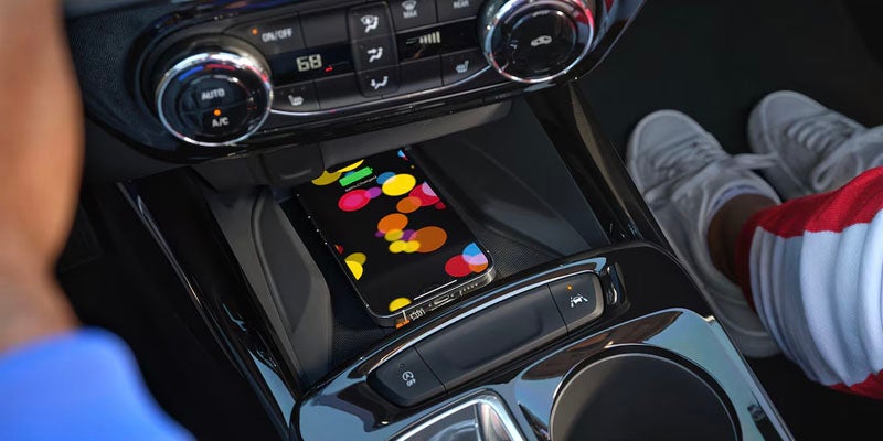 Close up view of the 2025 Chevy Trax's center console where a smartphone is charging wirelessly.