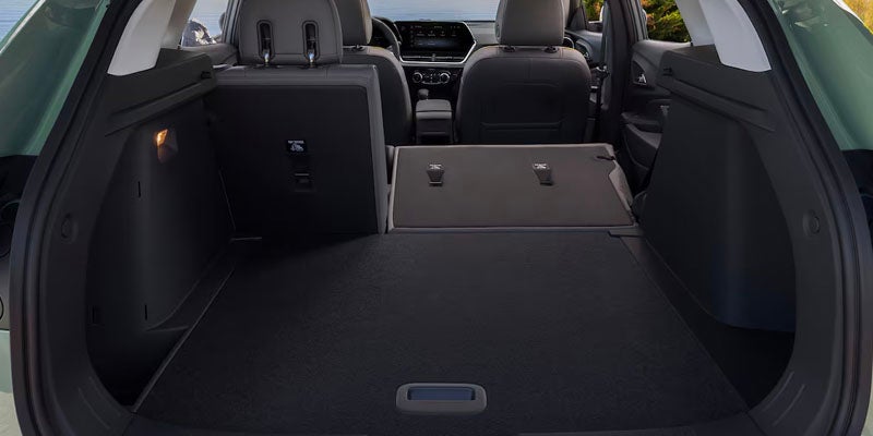 Rear interior view of the 2025 Chevy Trax. The trunk is open and two passenger seats are folded down for more cargo space.