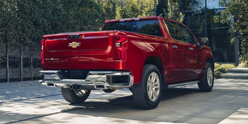 Front side view of the 2025 Chevrolet Silverado parked outside a home, there is a couple standing near the vehicle.
